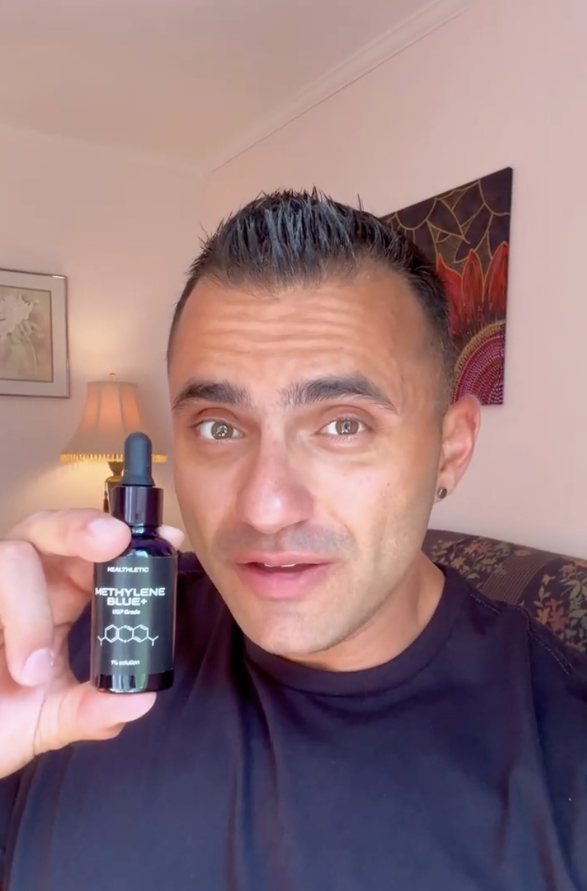 Person holding a bottle labeled 'Methylene Blue+' indoors.