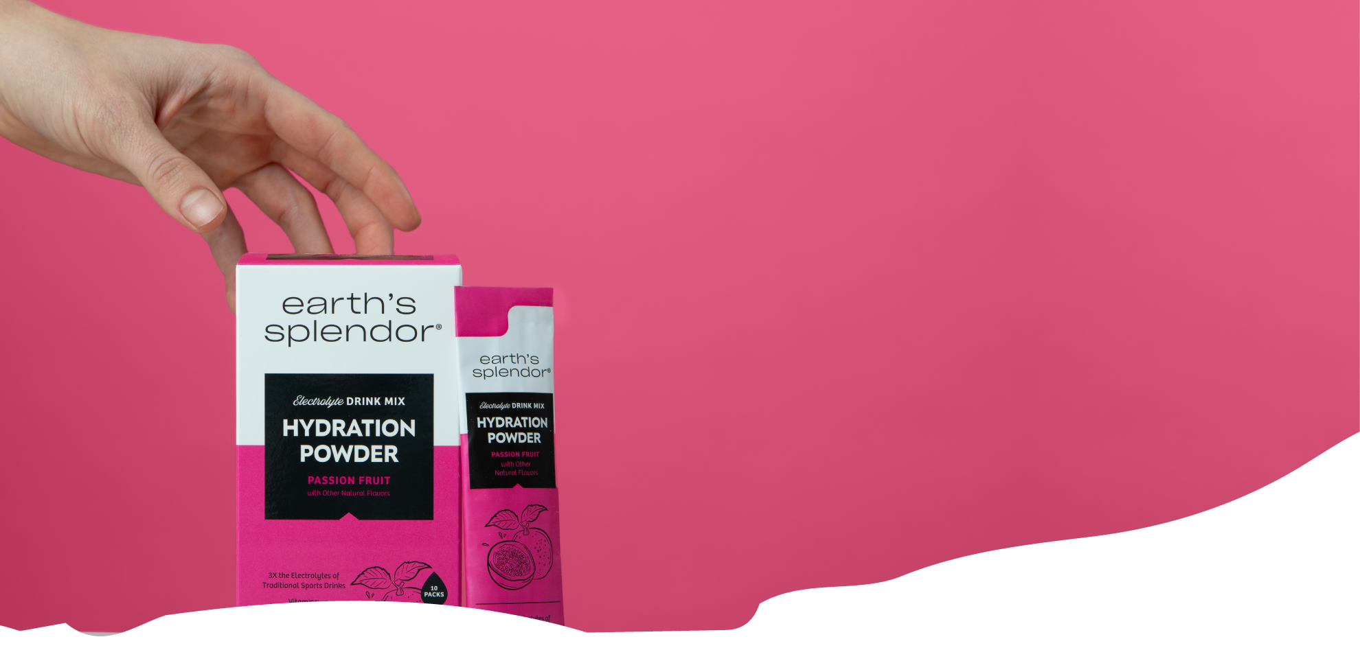 Hand holding Earth's Splendor hydration powder box against pink background.