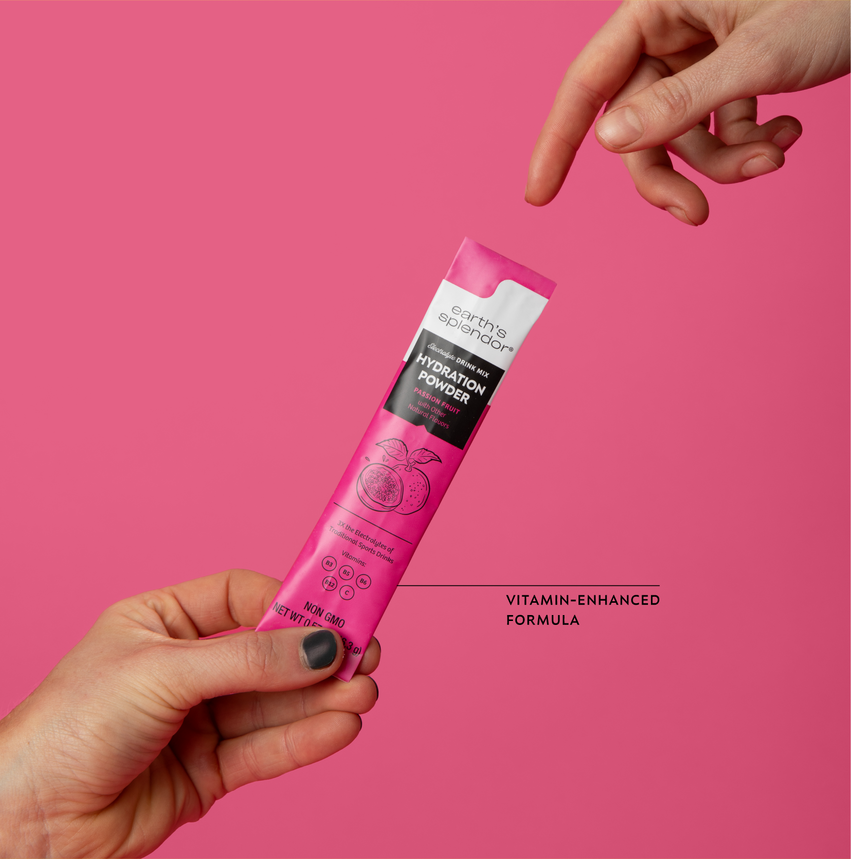 Hand holding pink hydration powder packet against pink background.