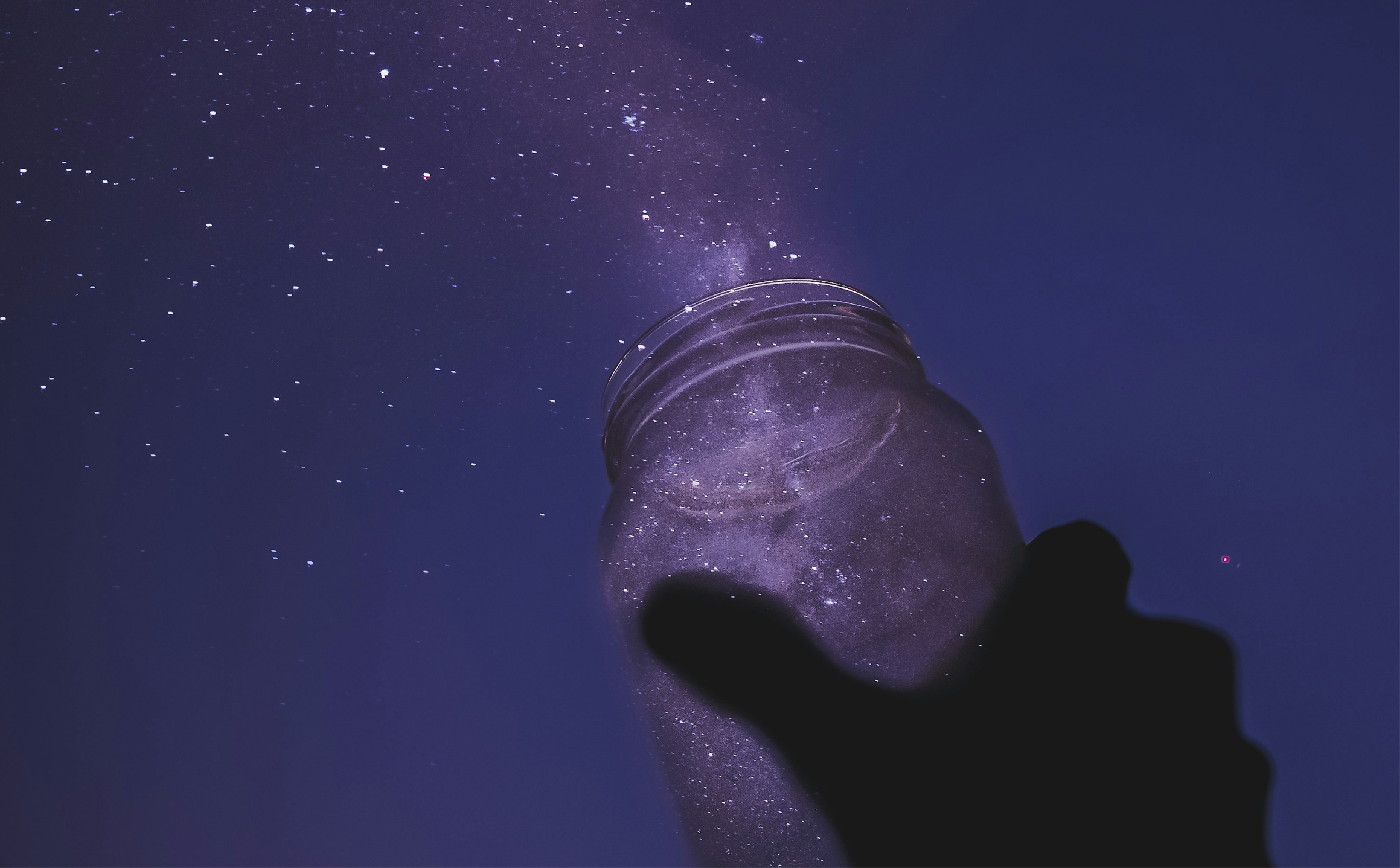 A jar appears to be pouring stars into a night sky.