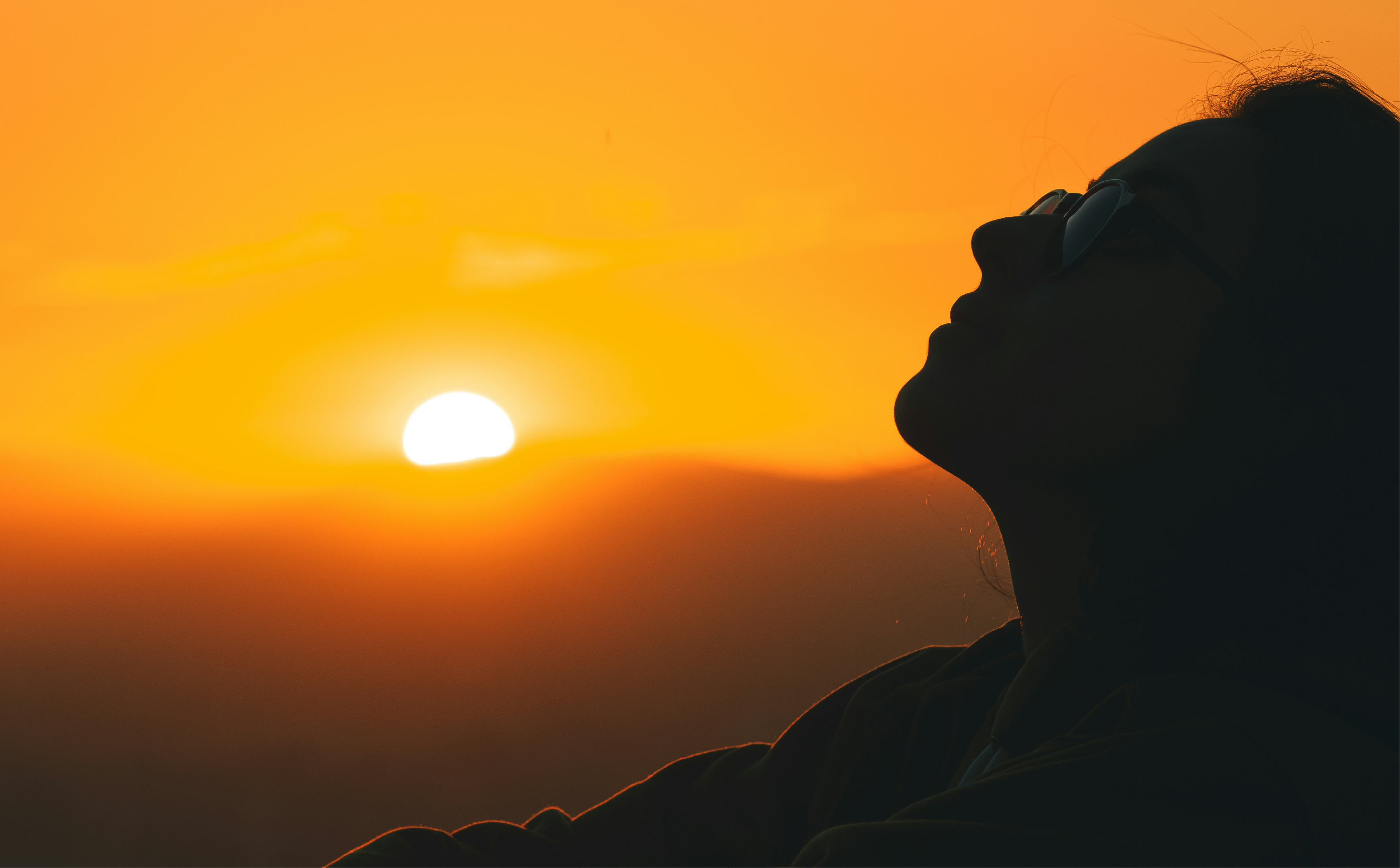 Silhouette of a person against a vibrant orange sunset.