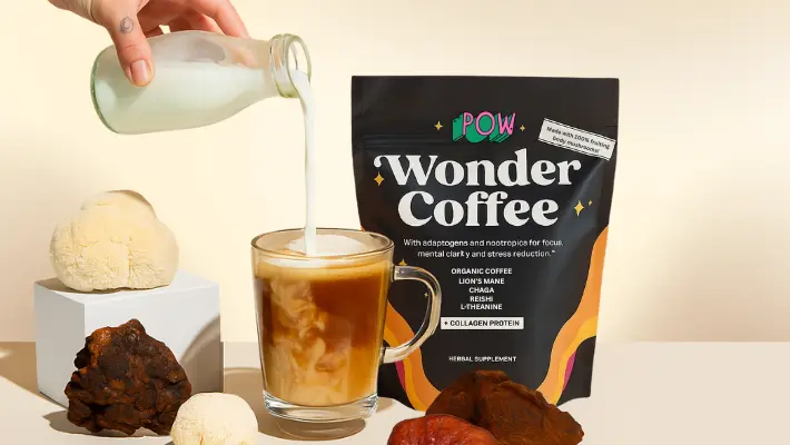 Milk being poured into iced coffee beside a Wonder Coffee package and mushrooms.