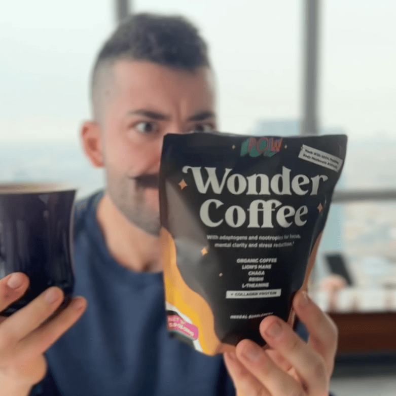 Person holding a Wonder Coffee package and a mug, looking at the package.
