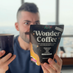 Person holding a coffee cup and a Wonder Coffee package indoors.