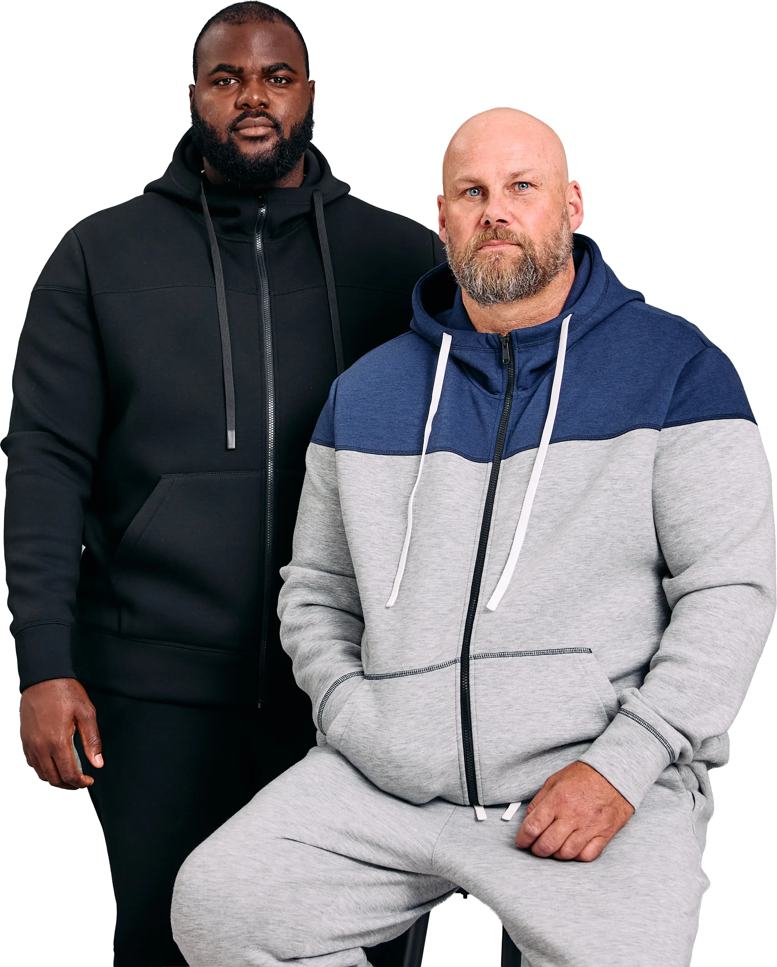 Two men model zip-up hoodies; one stands in black, the other sits in grey and blue.