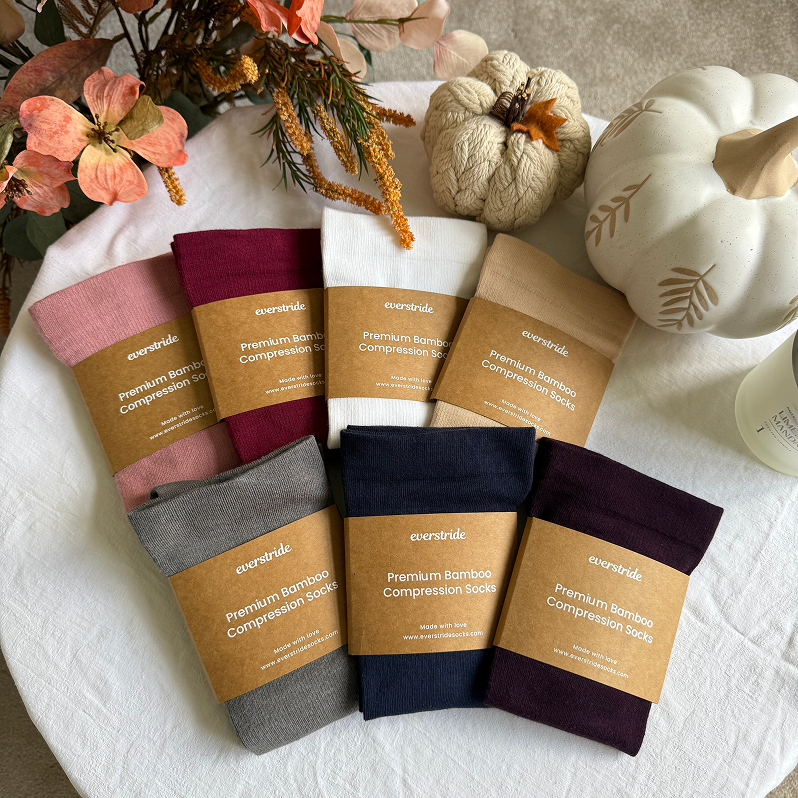 An overhead shot of several pairs of Everstride compression socks in various colors arranged with autumnal decorations.