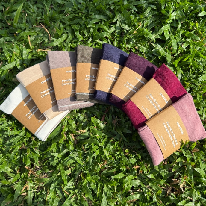 Several pairs of colorful socks in cardboard sleeves are fanned out on a patch of green grass.