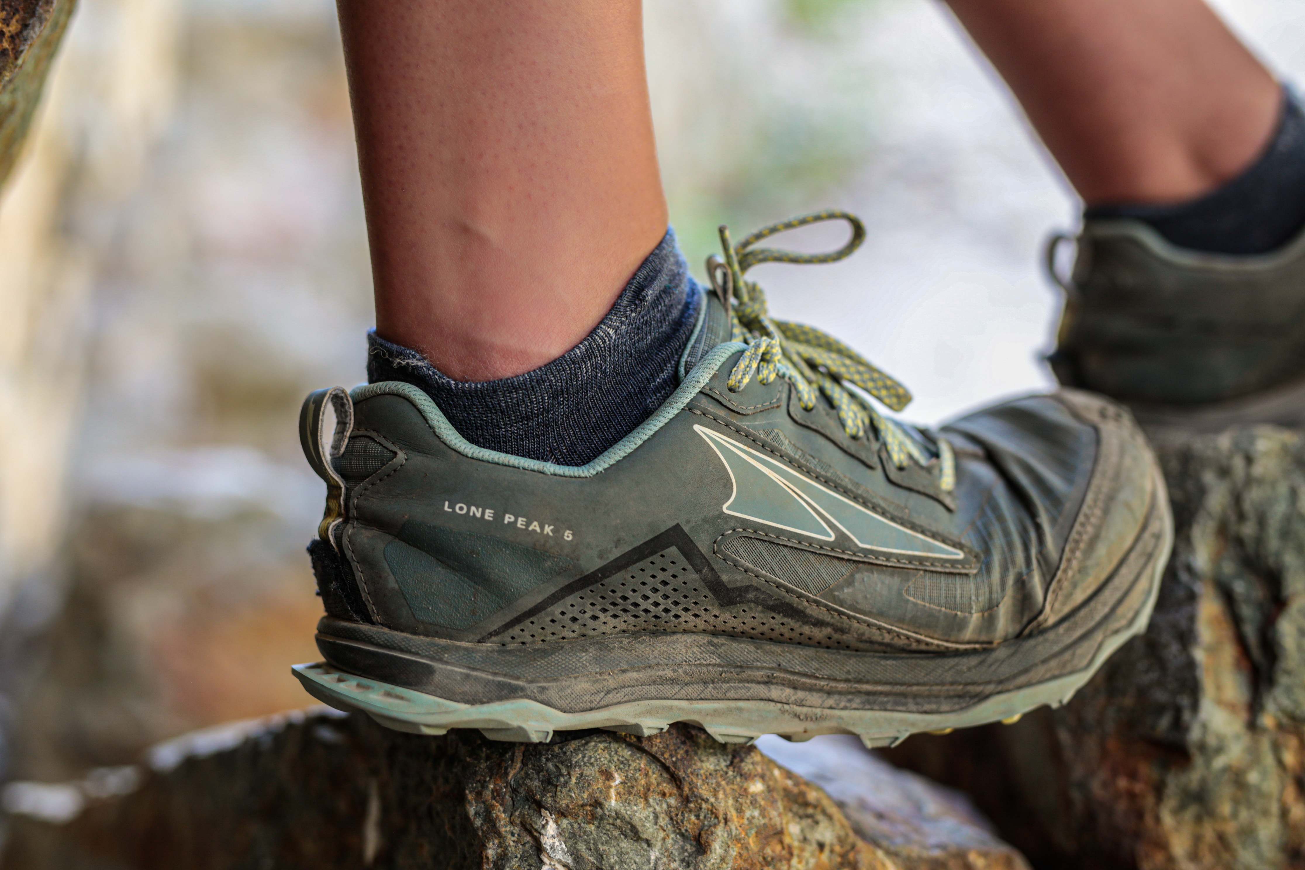 Close-up of a foot wearing a hiking shoe on a rock.