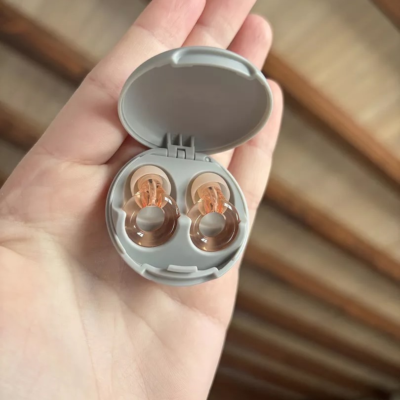 Hand holding a small case with two earplugs inside.