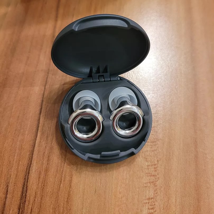 Open black case with two earbuds on a wooden surface.