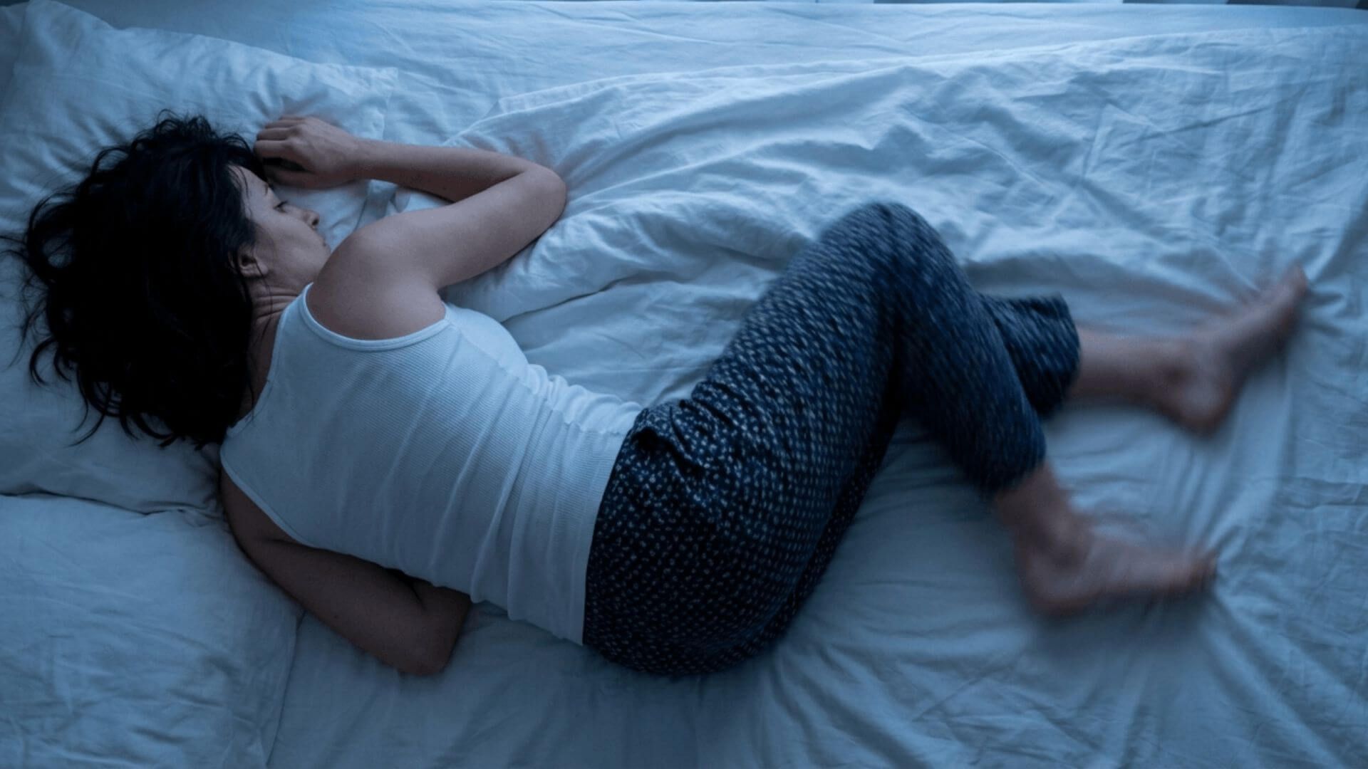 An overhead view of a woman tossing and turning restlessly in bed.