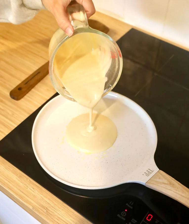 Pouring batter onto a non-stick pan on an induction cooktop.