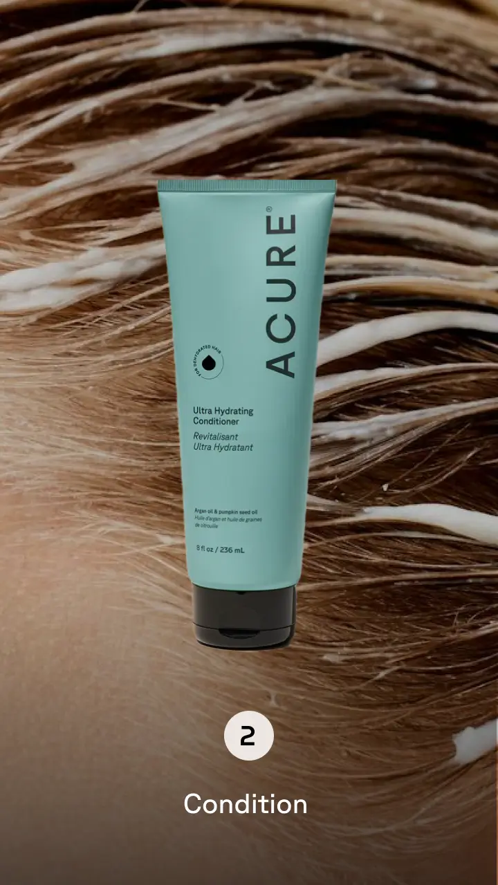 Person washing their blonde hair with blue product bottle in the foreground. Step 2 condition.