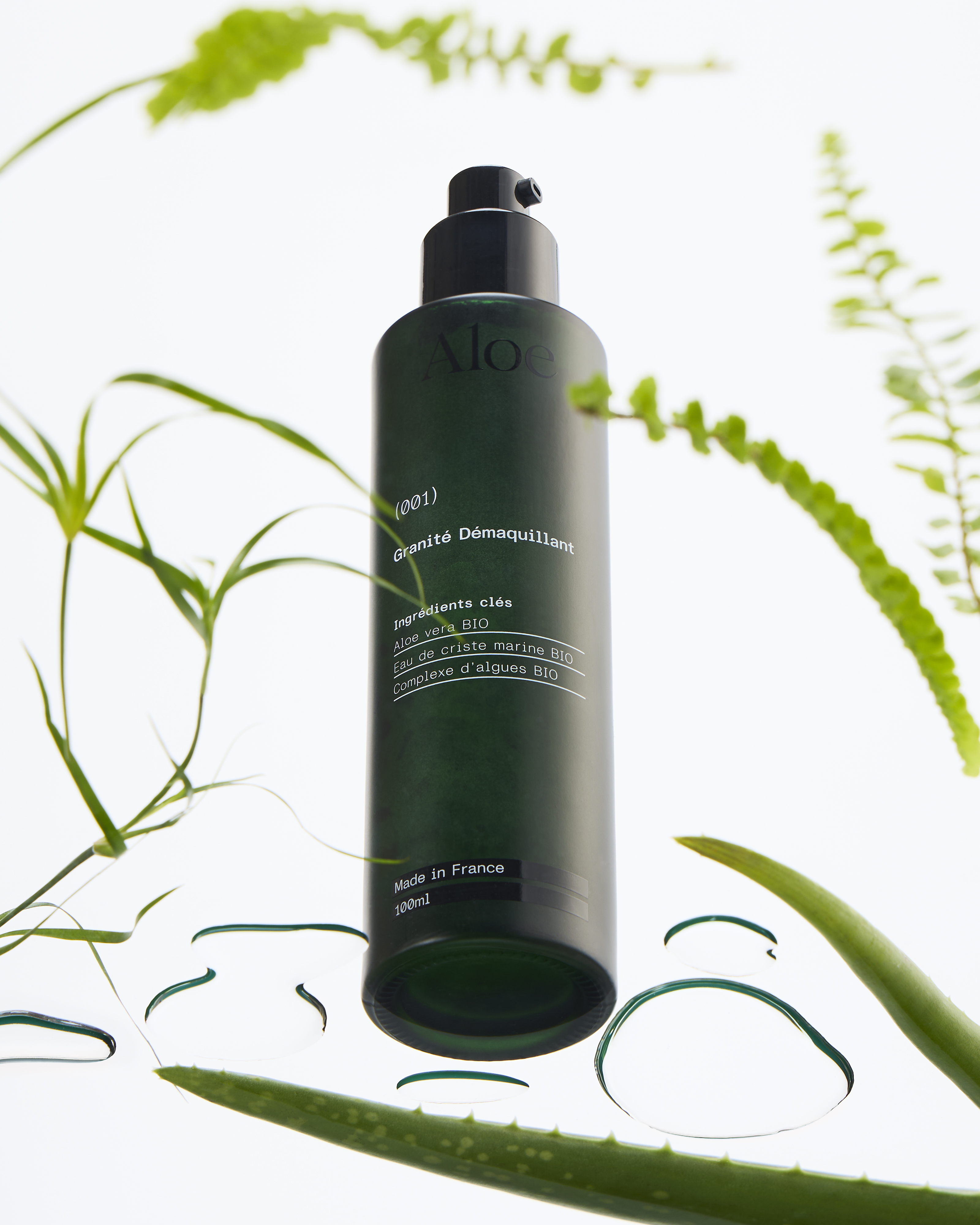 Green bottle of Aloe makeup remover surrounded by aloe leaves.