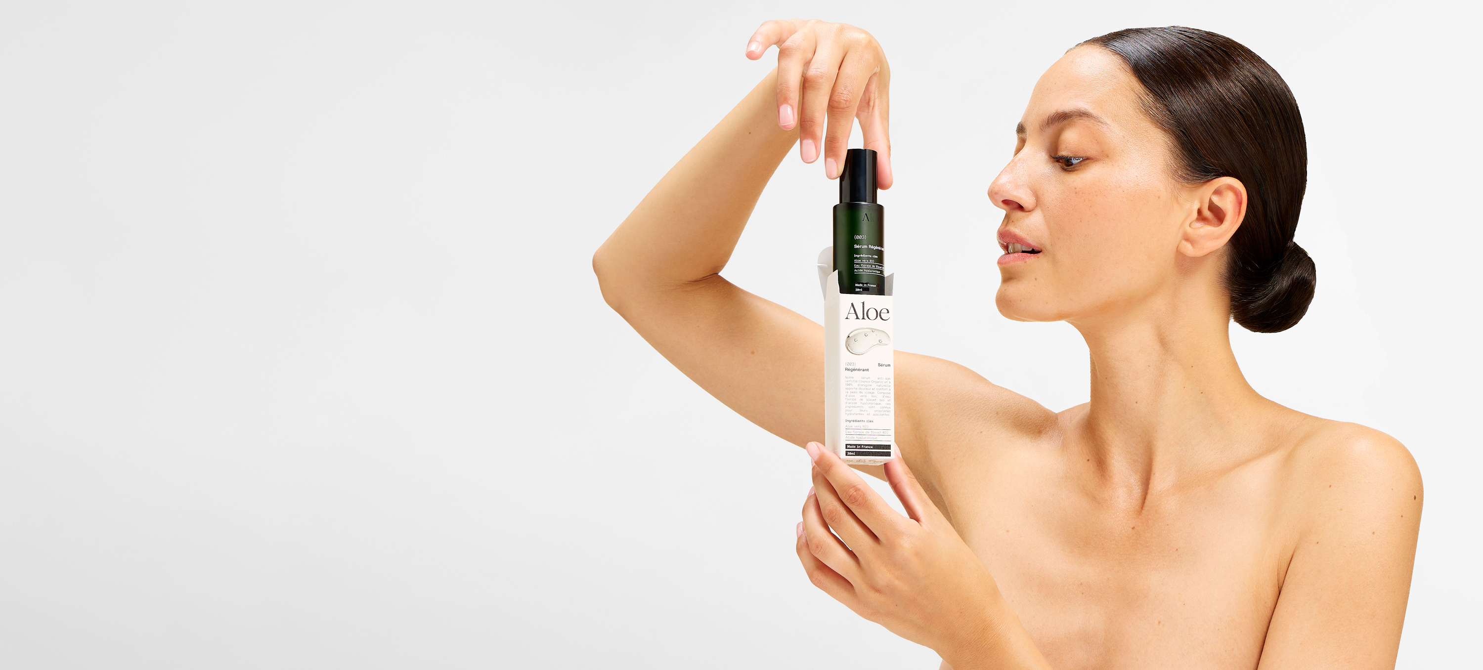 Person holding an Aloe skincare product against a plain background.