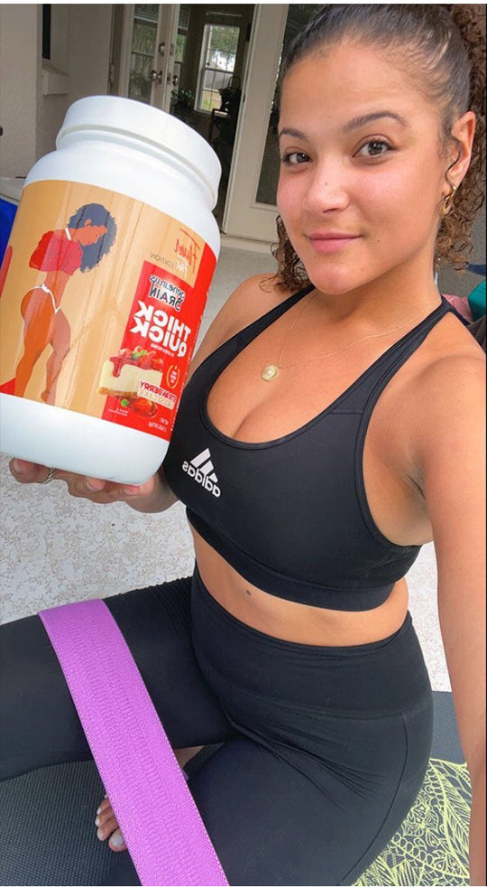A woman in workout clothes with a purple resistance band holds a large tub of supplements.