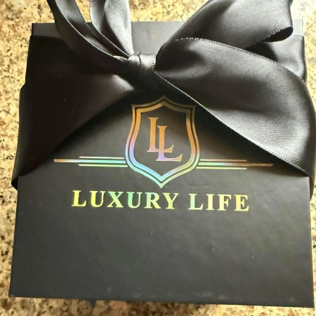 A black gift box with a large satin bow and 'Luxury Life' in holographic lettering.