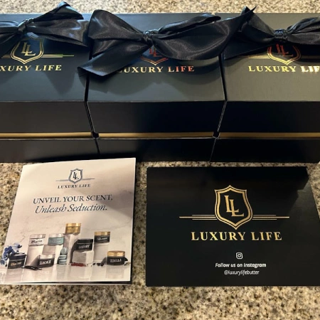 Three black 'Luxury Life' gift boxes with bows, alongside a matching brochure and business card.