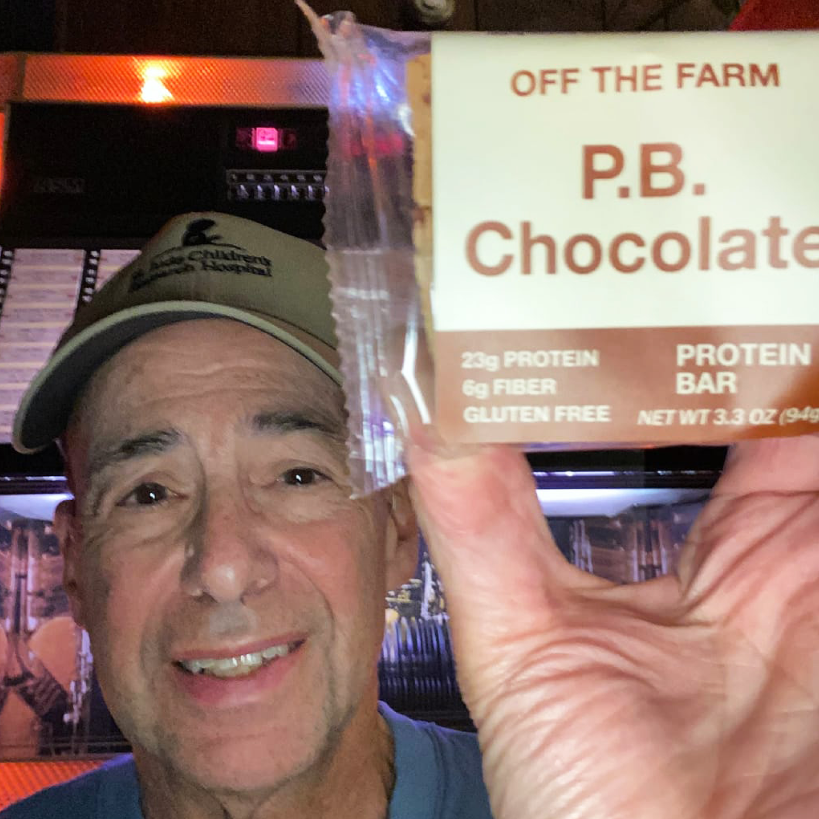 Man holding a P.B. Chocolate protein bar in front of a jukebox.