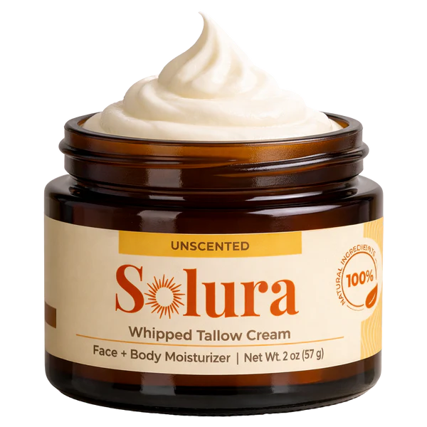 An open amber glass jar of Solura Unscented Whipped Tallow Cream with a swirl on top.