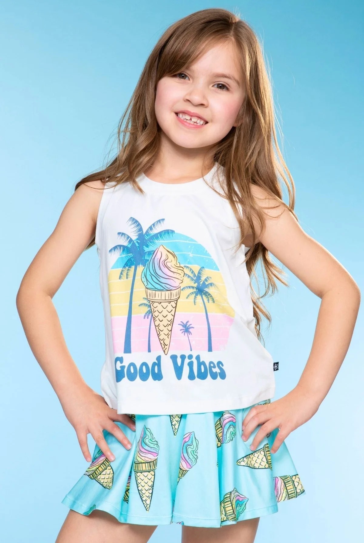 Smiling girl in a 'Good Vibes' shirt with ice cream and palm tree design.