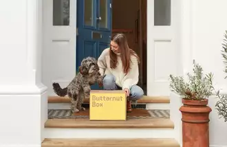 Woman sitting on steps with a dog and a Butternut Box.