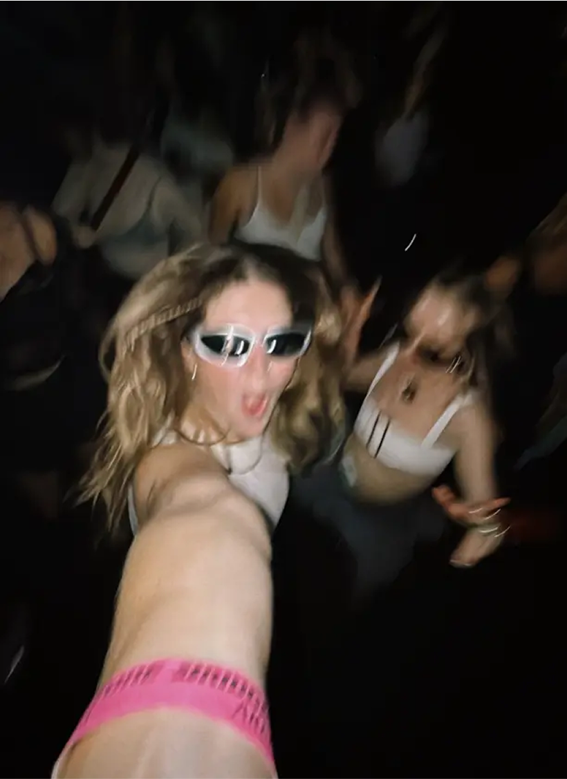 Blurred selfie of people dancing in a dark setting.