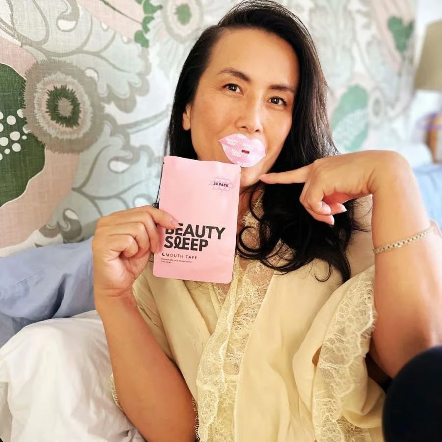 Person holding a pink package labeled 'Beauty Sleep' with mouth tape applied.