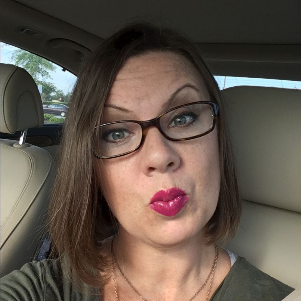 Person with glasses making a playful face inside a car.