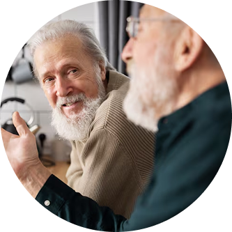 Two elderly men with beards having a conversation indoors.