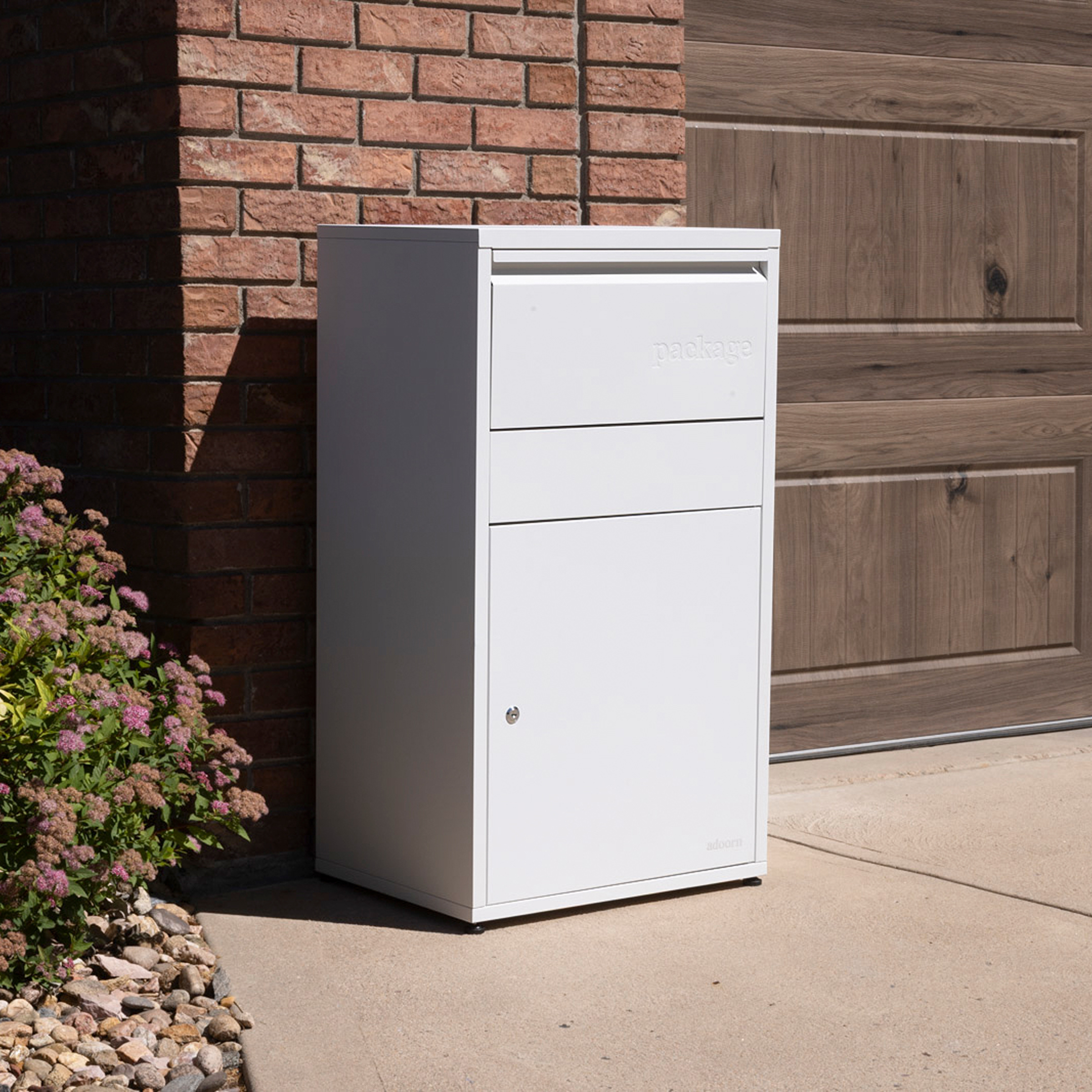 White package delivery box outside a brick wall and garage door.