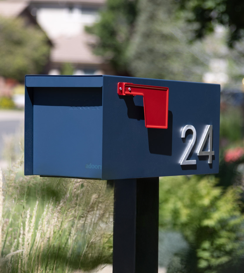Blue mailbox with red flag and number 24, outdoors.