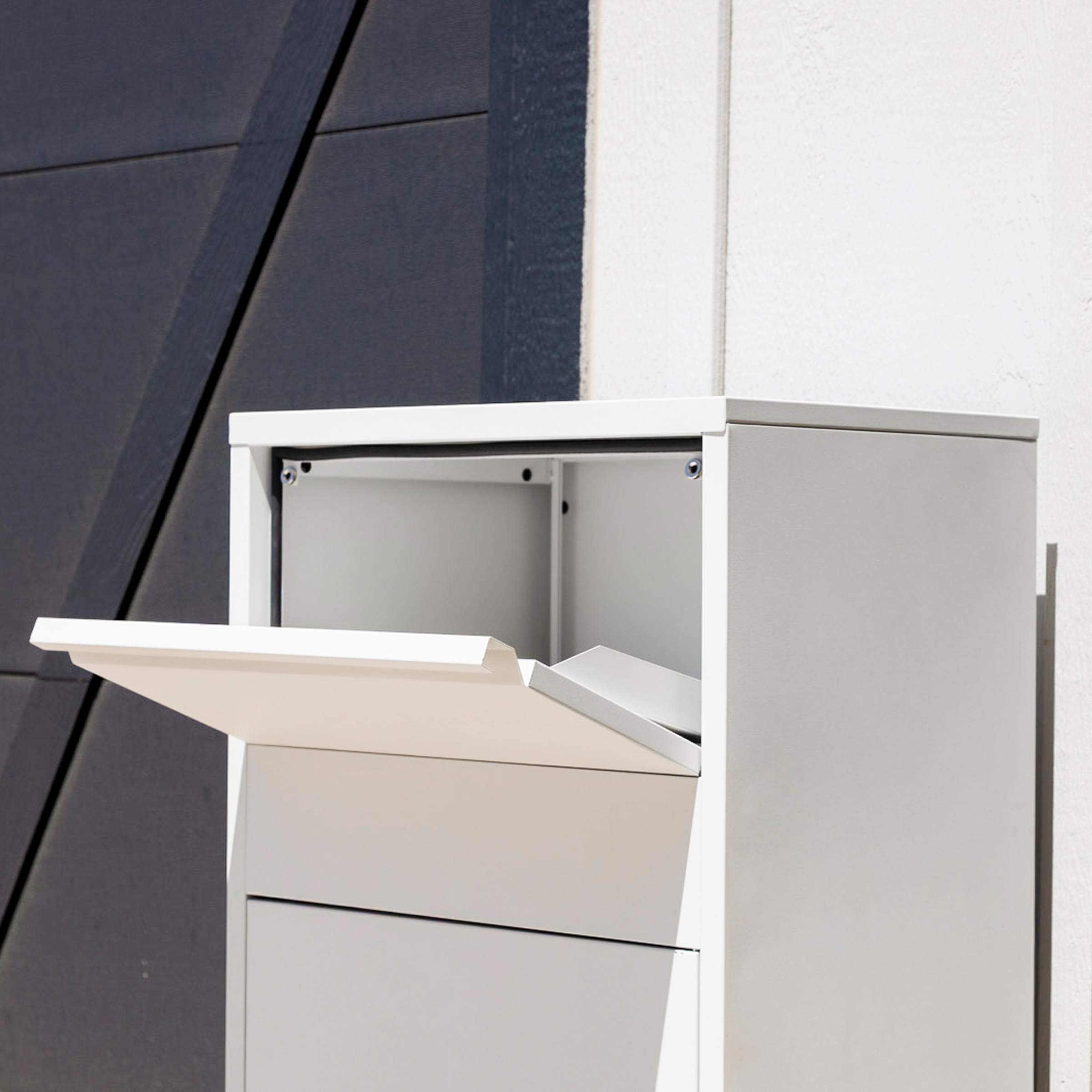 White mailbox with open lid against a dark and light wall.
