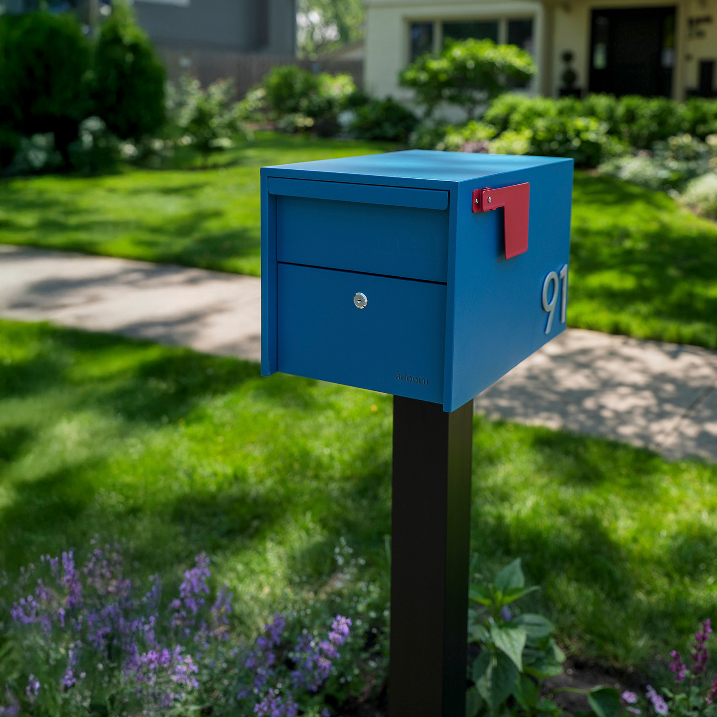 Blue mailbox with red flag in a garden setting.