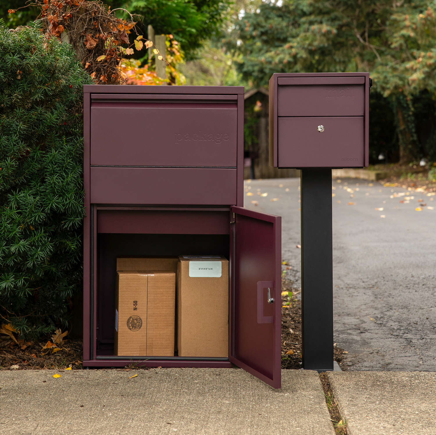 Maroon package box with open door revealing parcels inside on a driveway.