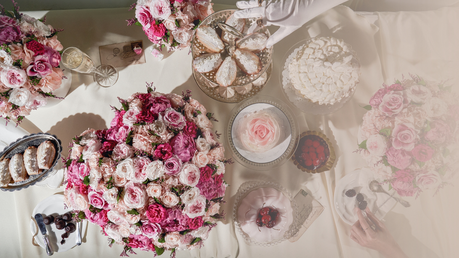 Floral arrangements and desserts arranged on a decorated table with a white tablecloth.