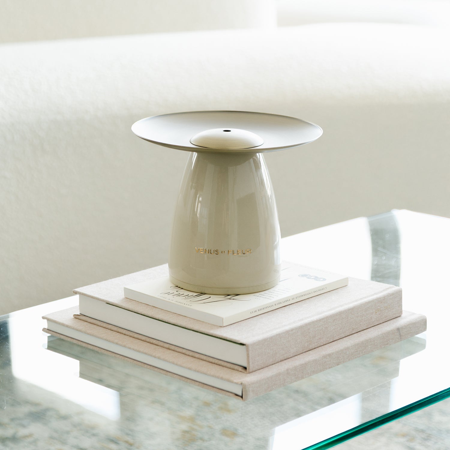 A ceramic diffuser on stacked books on a glass table.