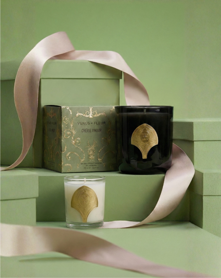 Two decorative candles, one black and one white, sit next to a green gift box with a pink ribbon.