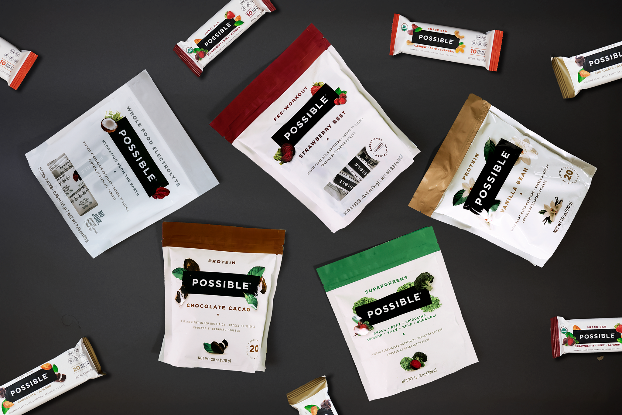 A variety of 'Possible' brand nutritional powders and snack bars arranged on a dark grey surface.