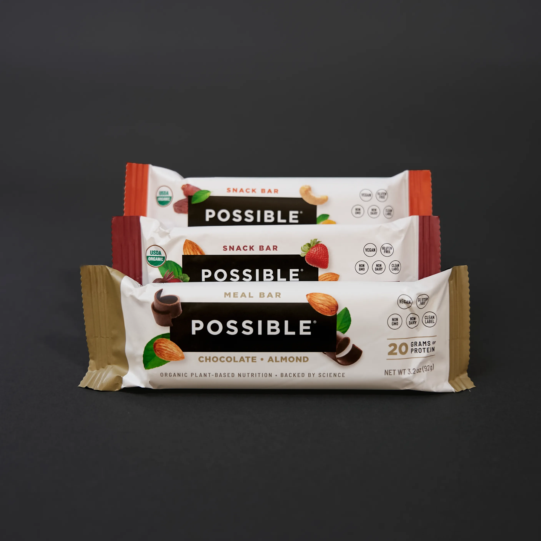 A stack of three POSSIBLE brand meal and snack bars against a dark background.