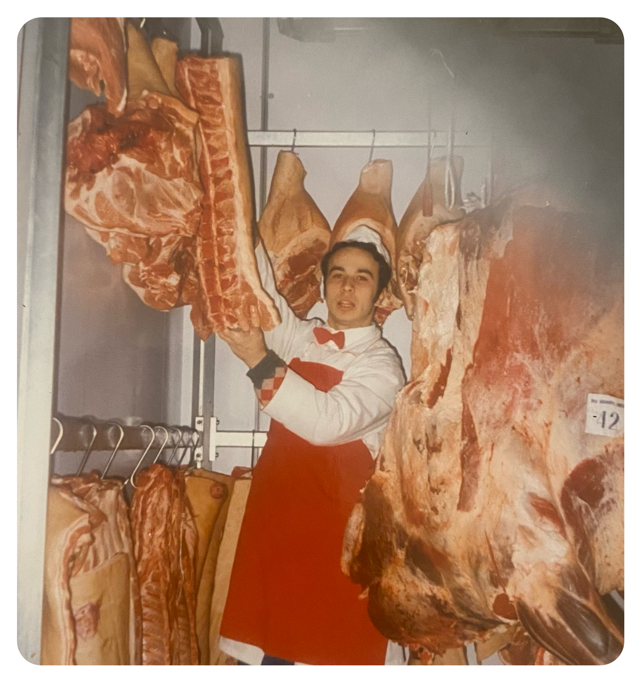 Butcher holding a large piece of meat in a cold storage room.