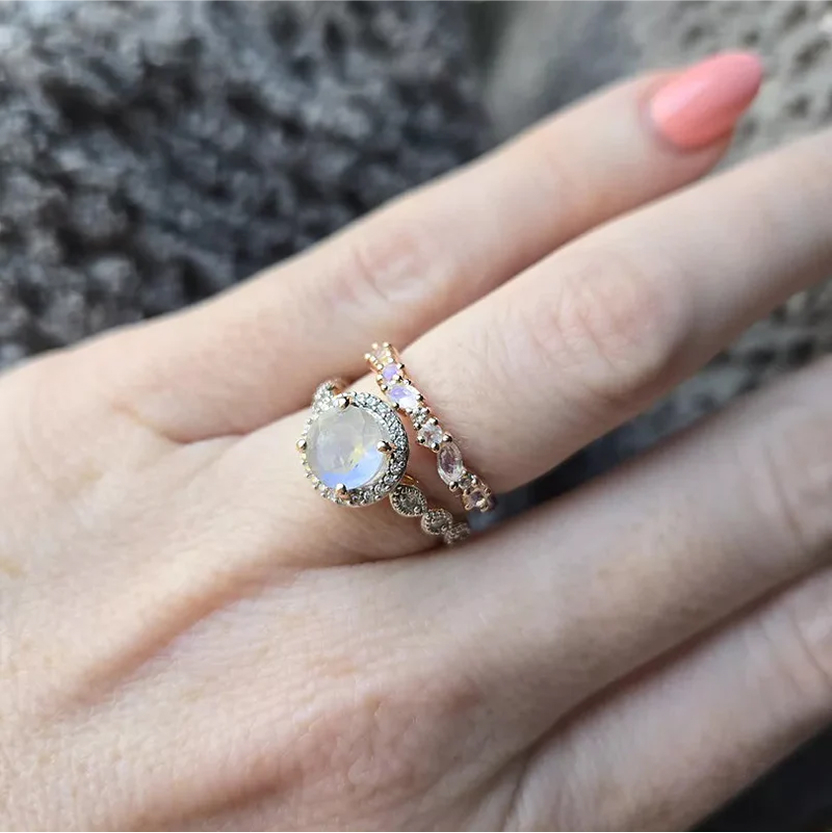 Hand wearing two ornate rings with gemstones.