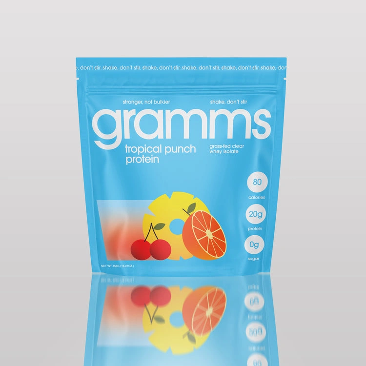A blue pouch of Gramms tropical punch protein powder sitting on a reflective surface against a plain background.