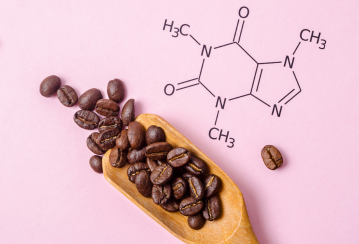 Coffee beans on a wooden spoon with a caffeine molecule diagram on a pink background.