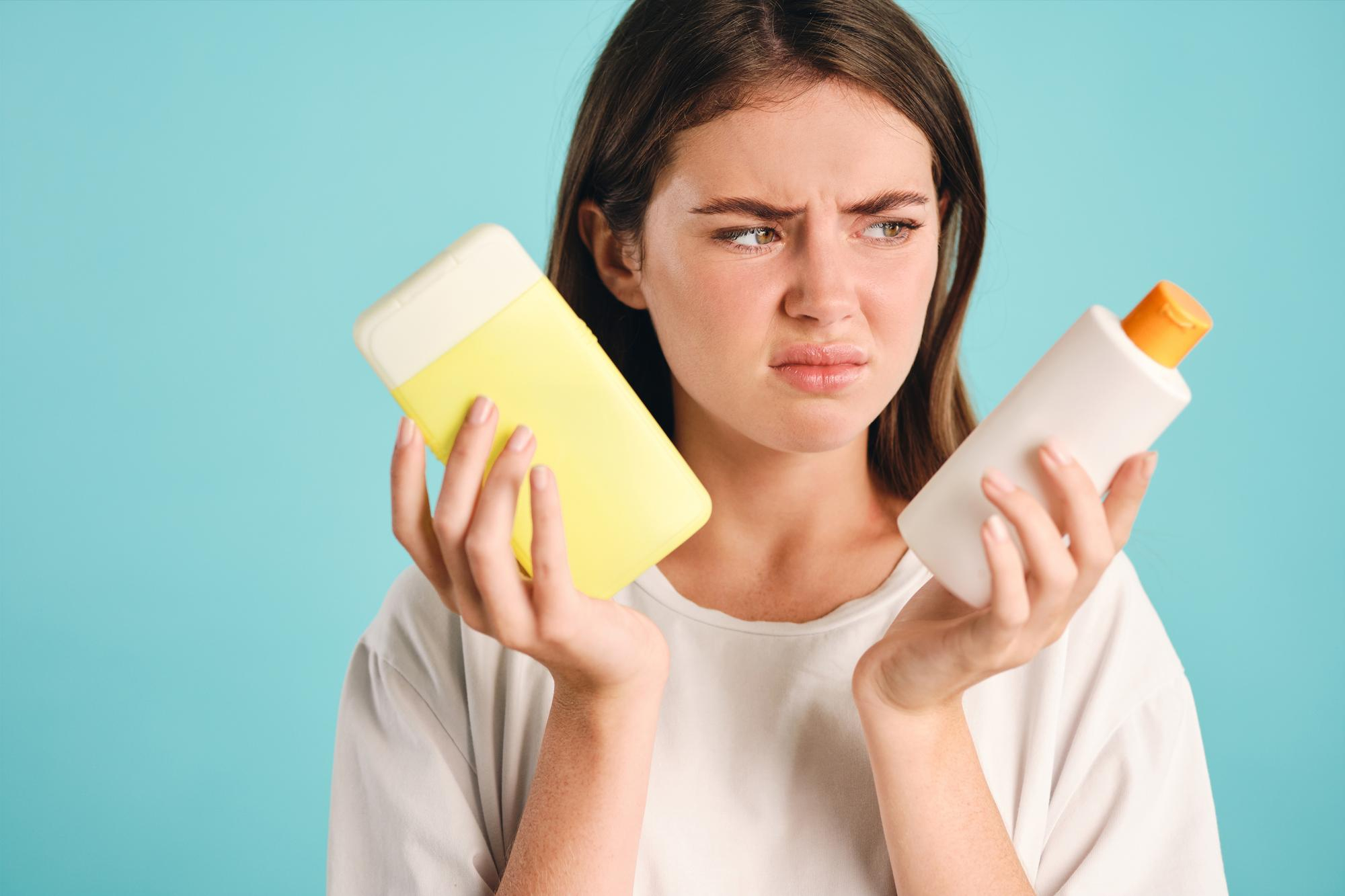 Person holding two bottles with a confused expression.