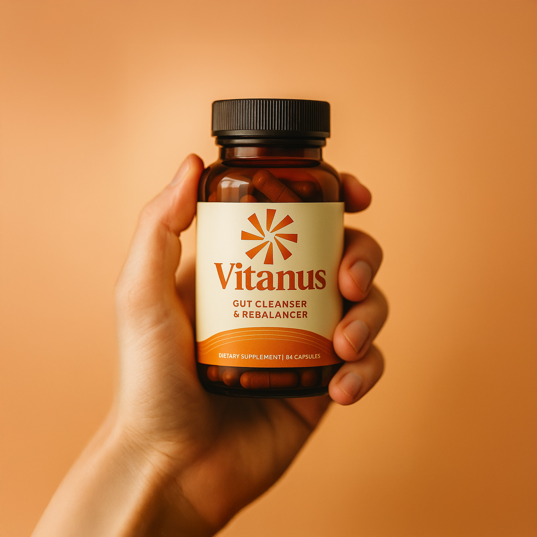 Hand holding a bottle labeled 'Vitanus Gut Cleanser & Rebalancer' with capsules inside.