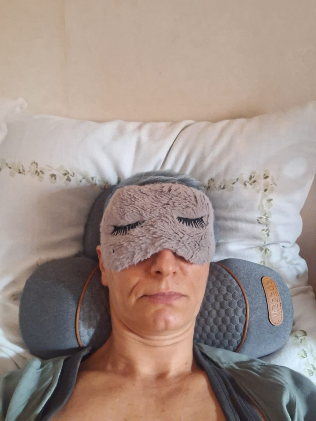 Person lying down with a sleep mask and neck pillow.