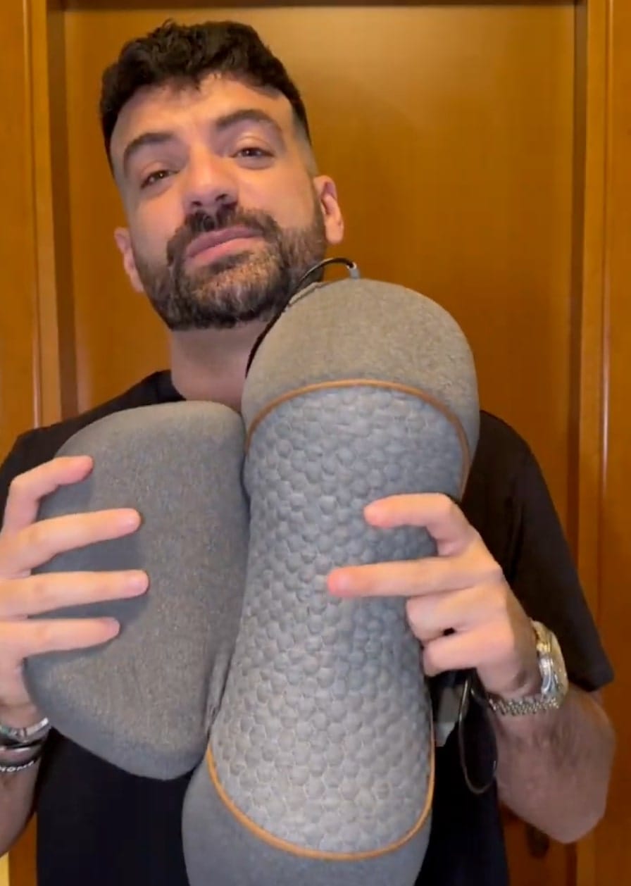 Person holding two gray ergonomic cushions.