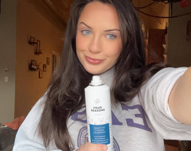 Person holding a can of Four Reasons hairspray indoors.