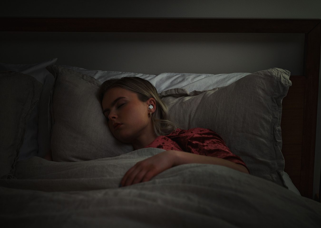 Person sleeping in bed wearing wireless earbuds.